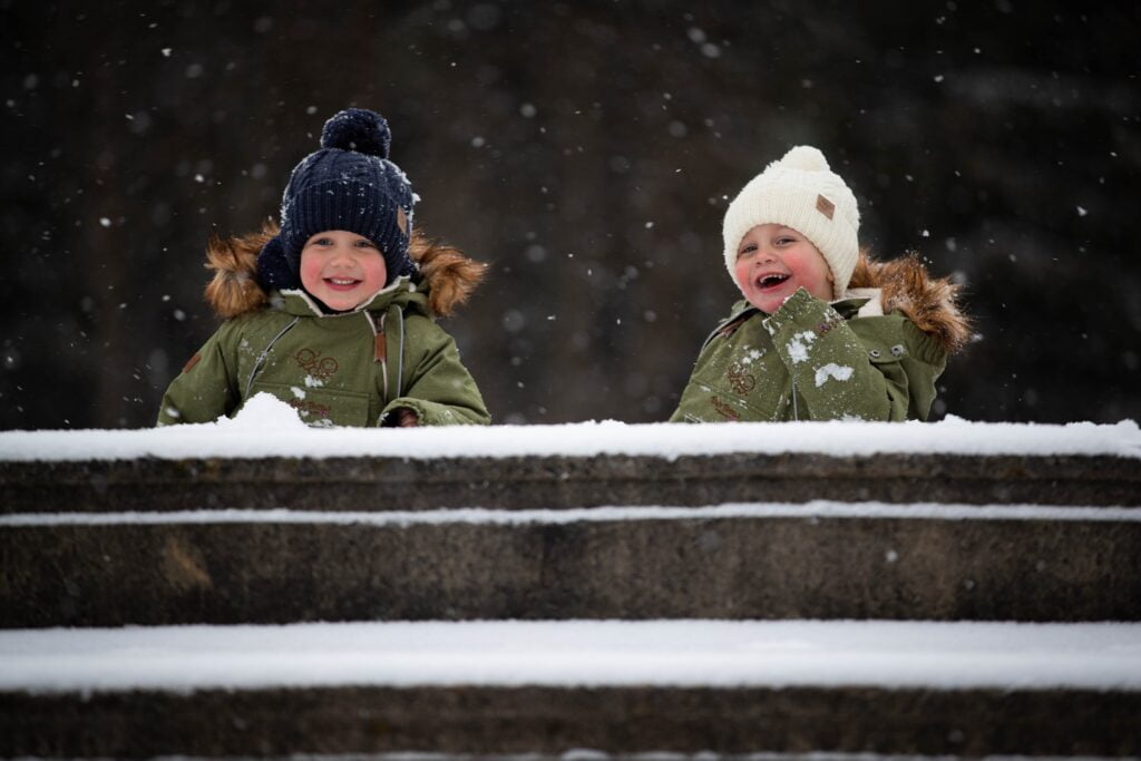 Bilde av to barn, gutter, i alderen 5 og 3 år. Ute i snøen og koser seg. Tips for en god vintertur er riktige klær.