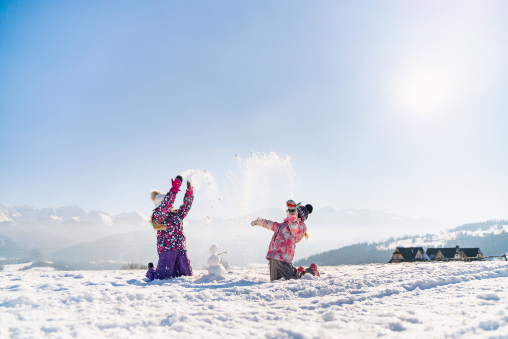 To barn som koser seg i snøen. Kaster snø i luften og har bygd en liten snømann. Godt tips til vintertur er å gjøre det til en lek.
